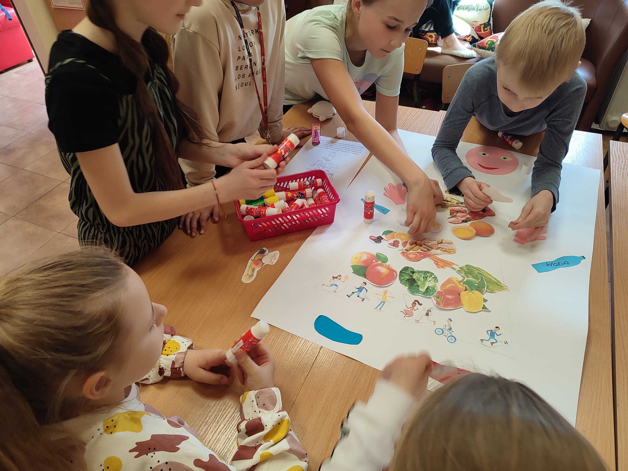 Dzieci w grupie przygotowują piramidę zdrowego żywienia z zebranych wcześniej materiałów.