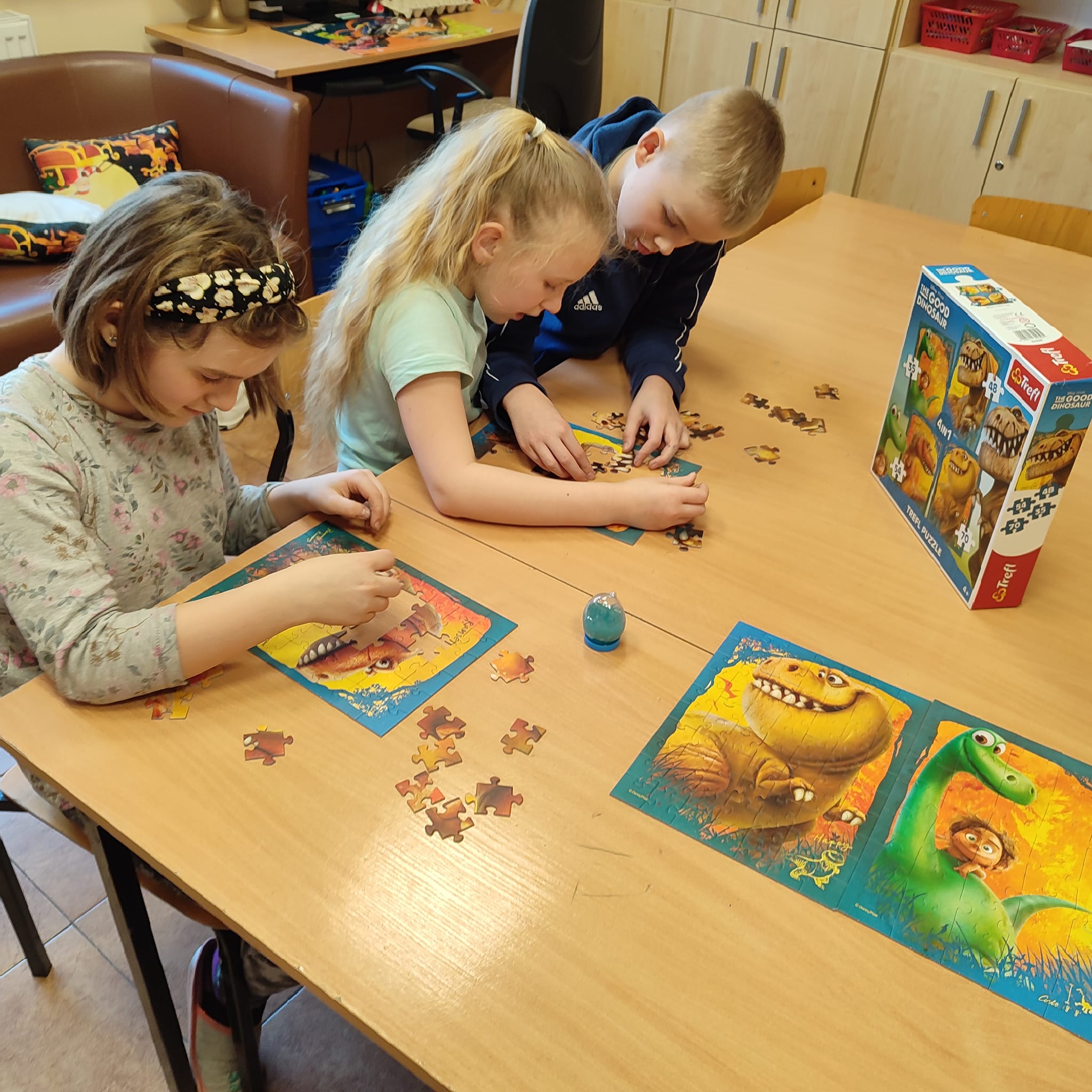 Troje dzieci układa puzzle
