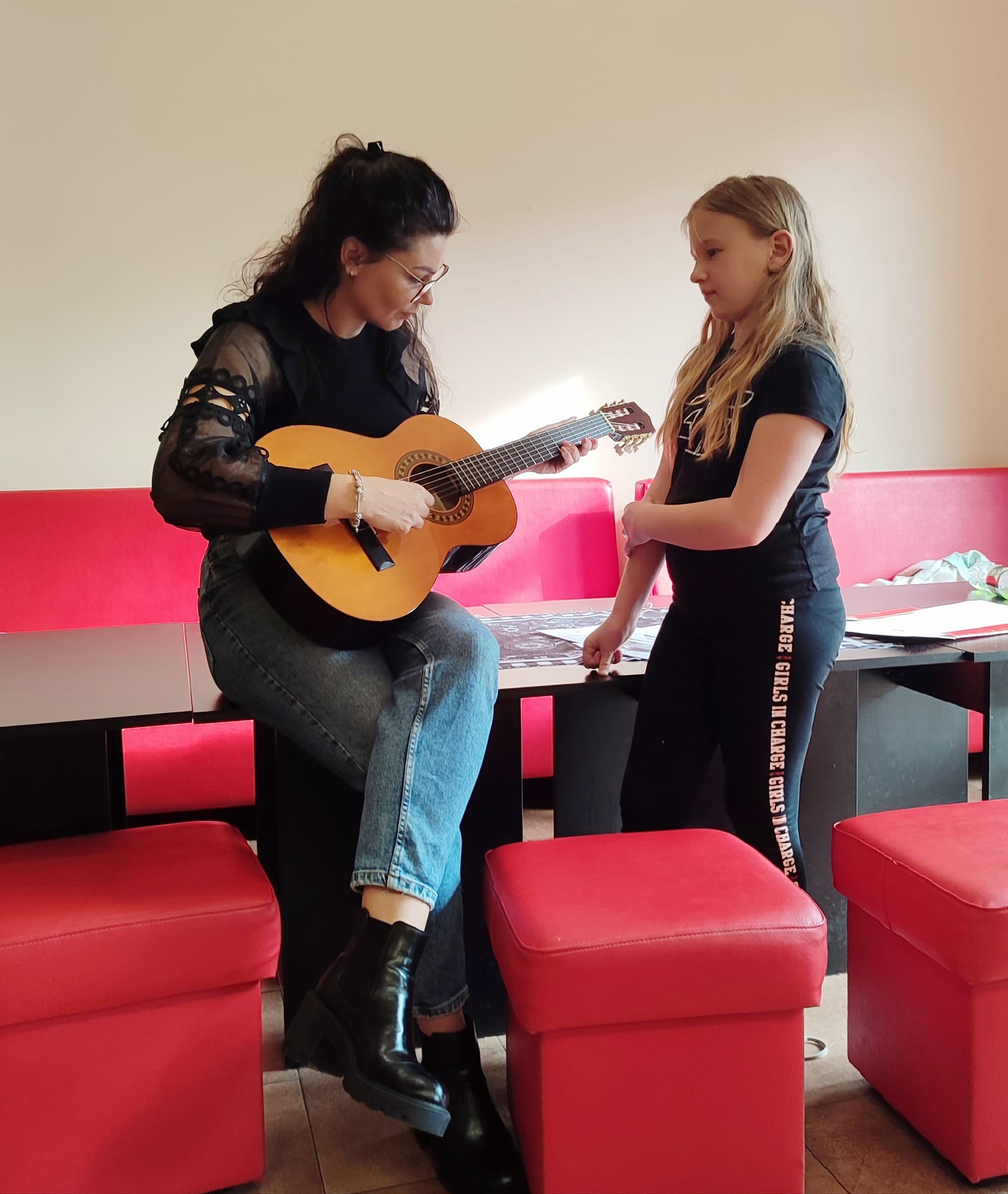 Dziewczynka uczy Wychowawczynię gry na gitarze